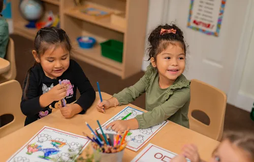 Children coloring and learning together at classroom table